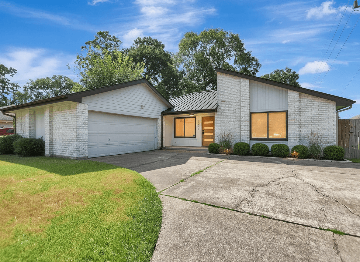 Exterior of a modern house with limewashed brick, charcoal metal roof, white oak pivot door, and clean landscaping.