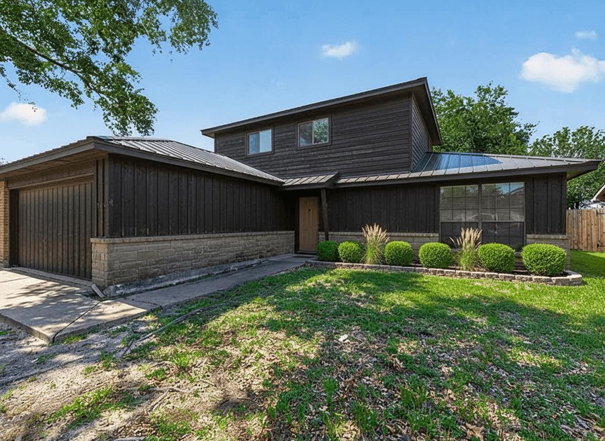 Exterior of a Southern California style home with dark vertical timber siding, a low stone base, and a charcoal metal roof.
